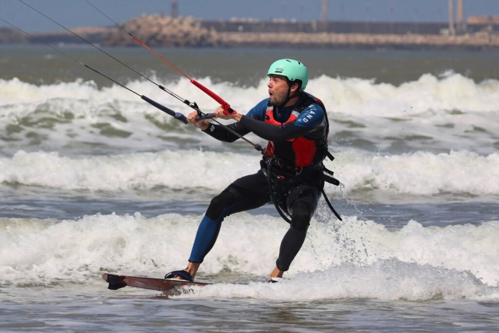 A kitesurfer riding the waves in Essaouira, successfully completing a waterstart during a beginner kitesurf lesson.