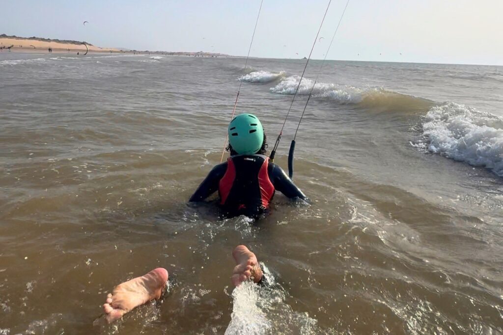A beginner kitesurf student body dragging through the ocean in Essaouira, learning kite control in the water during lesson two.