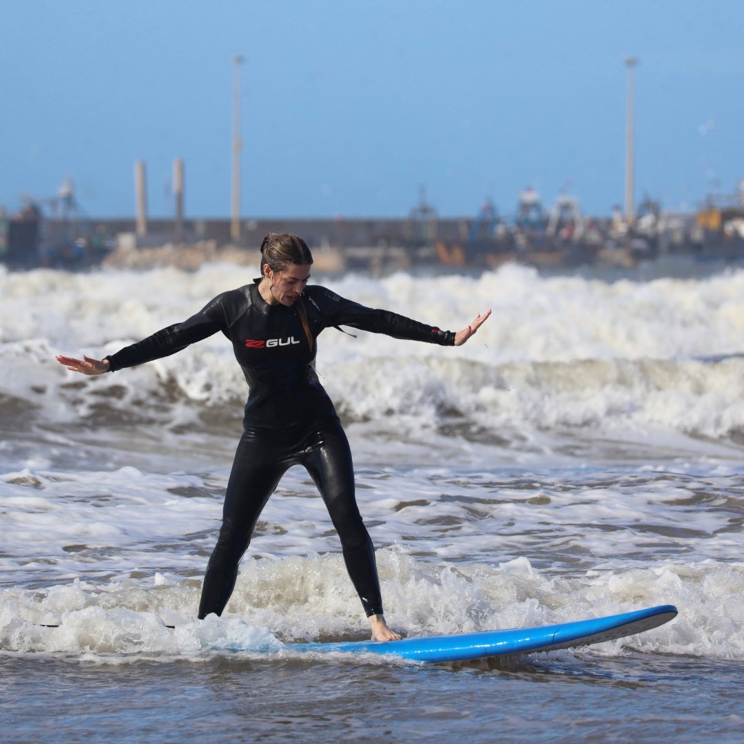 A female surfer catching a wave during her group surf lesson in Essaouira