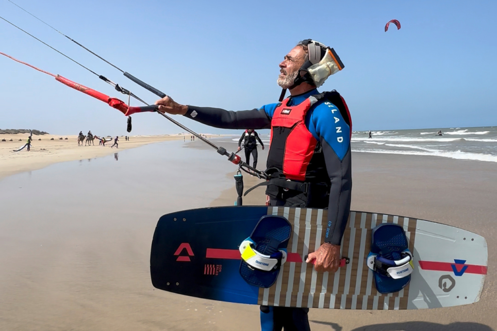 A kitesurfer on a private lesson in Essaouira, holding a kitesurf board.