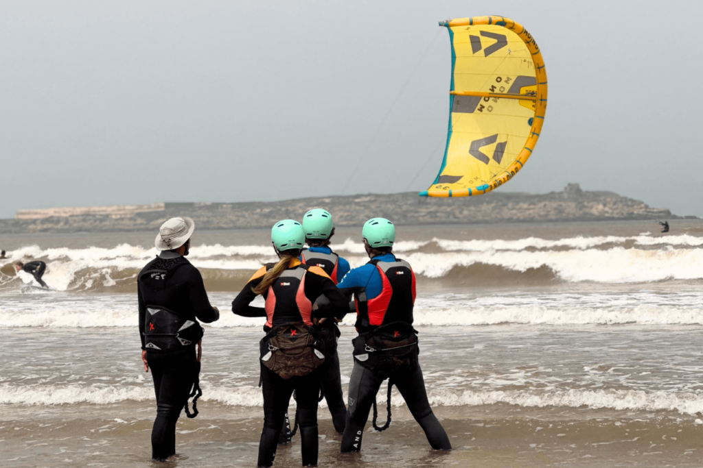 Three friends during their group kitesurfing lesson in Essaouira, learning to control the kite.