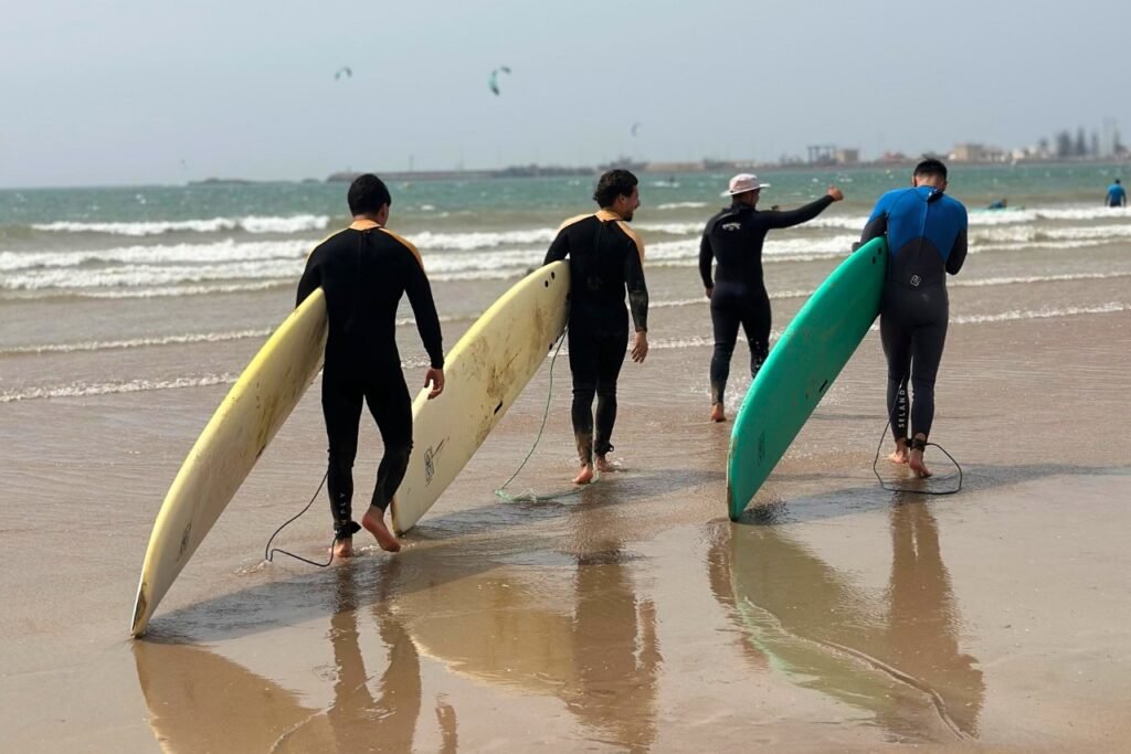 Beginner surfers carrying their boards into the water in Essaouira for their first surf lesson.