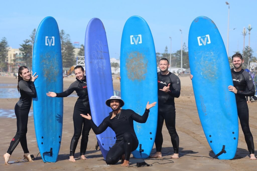 A group of beginner surfers posing with their boards and instructor on Essaouira beach, after their first surf lesson.
